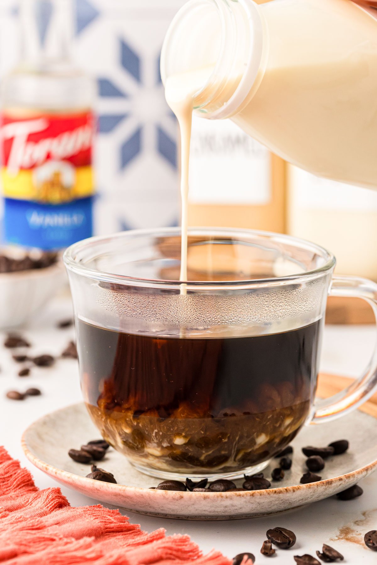 Creamer being poured into black coffee in a mug.