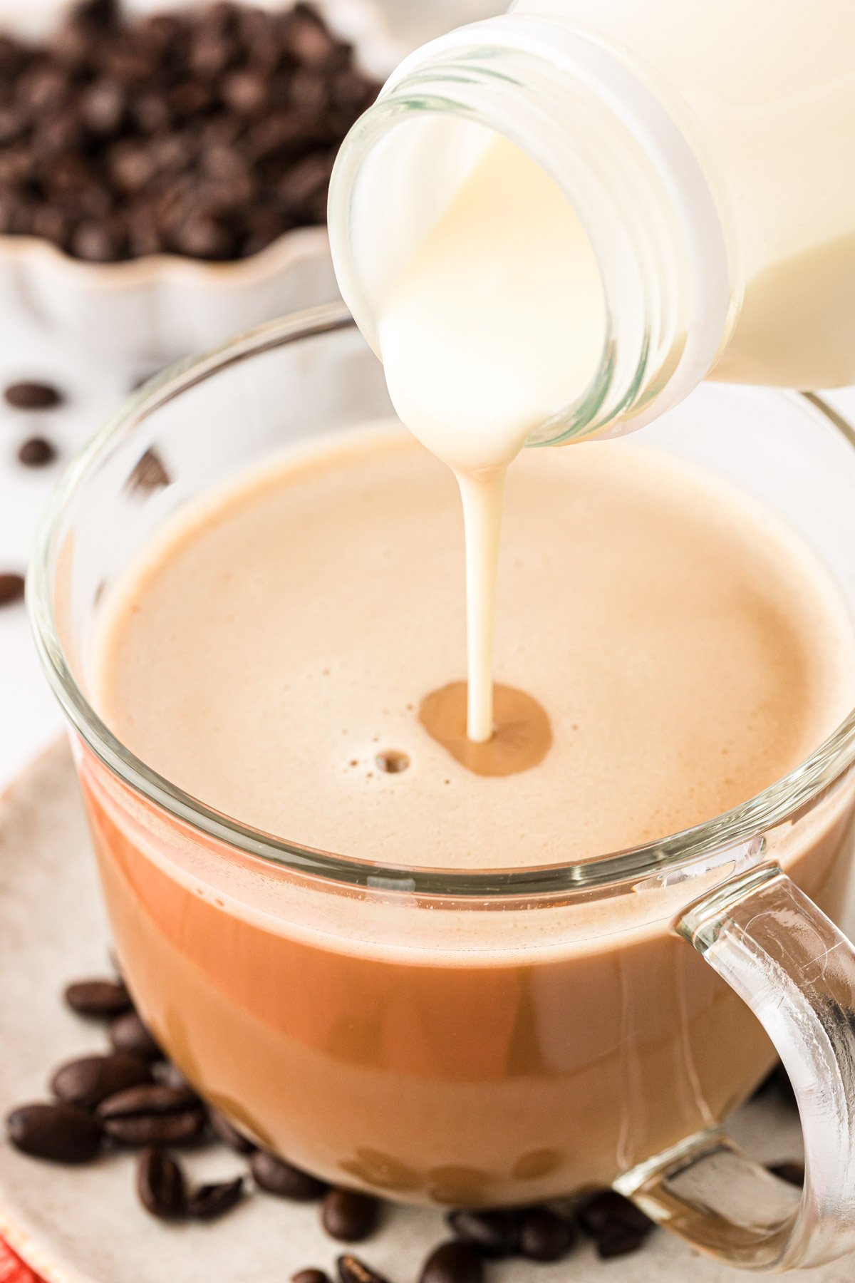 Creamer being poured into a mug with coffee.