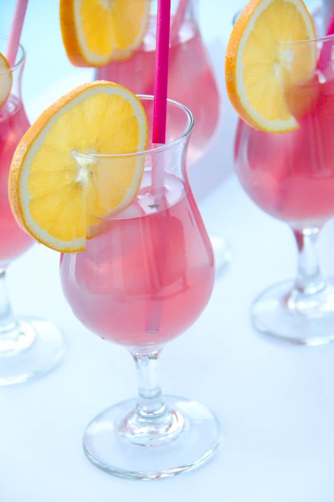A glass filled with punch, a lemon slice and a straw