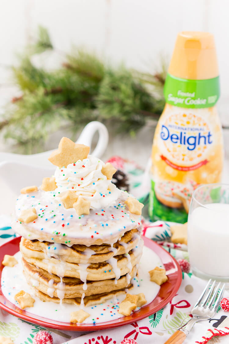 These Sugar Cookie Pancakes will add holiday cheer to your morning routine. Trade in traditional buttermilk for thick, fluffy, and sweet ricotta based pancakes laced with sugar cookie creamer, and topped with baked sugar cookies, icing, whipped cream, and sprinkles!