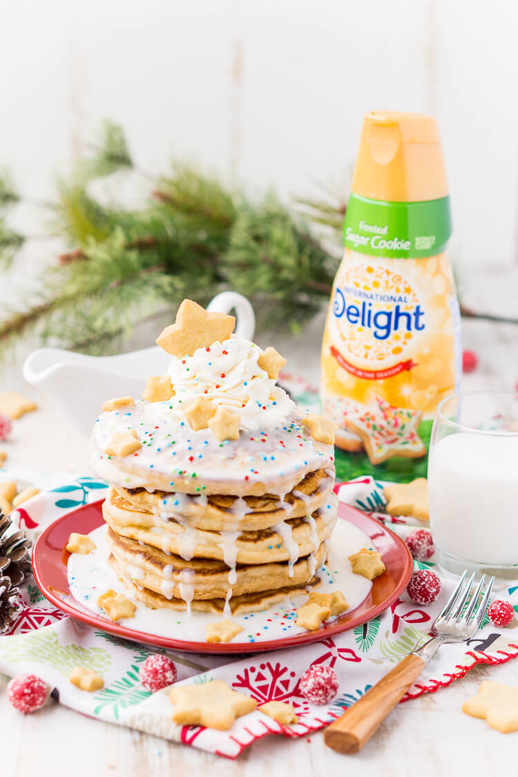 These Sugar Cookie Pancakes will add holiday cheer to your morning routine. Trade in traditional buttermilk for thick, fluffy, and sweet ricotta based pancakes laced with sugar cookie creamer, and topped with baked sugar cookies, icing, whipped cream, and sprinkles!