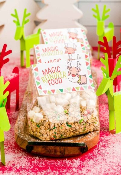 Close up photo of bags of reindeer food on a wooden tray with paper reindeer around them.