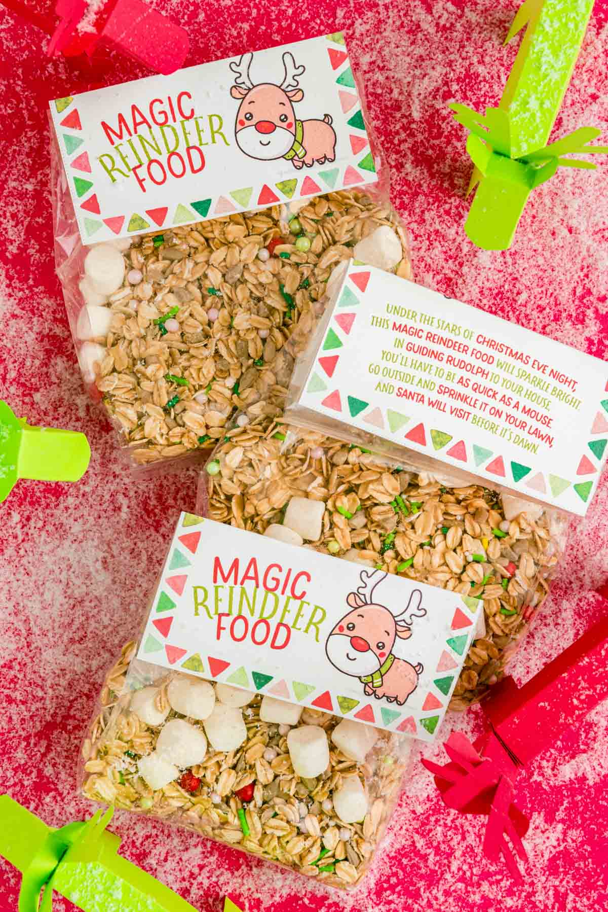 Overhead photo of bags of magic reindeer food on a red table with fake snow and paper reindeer.