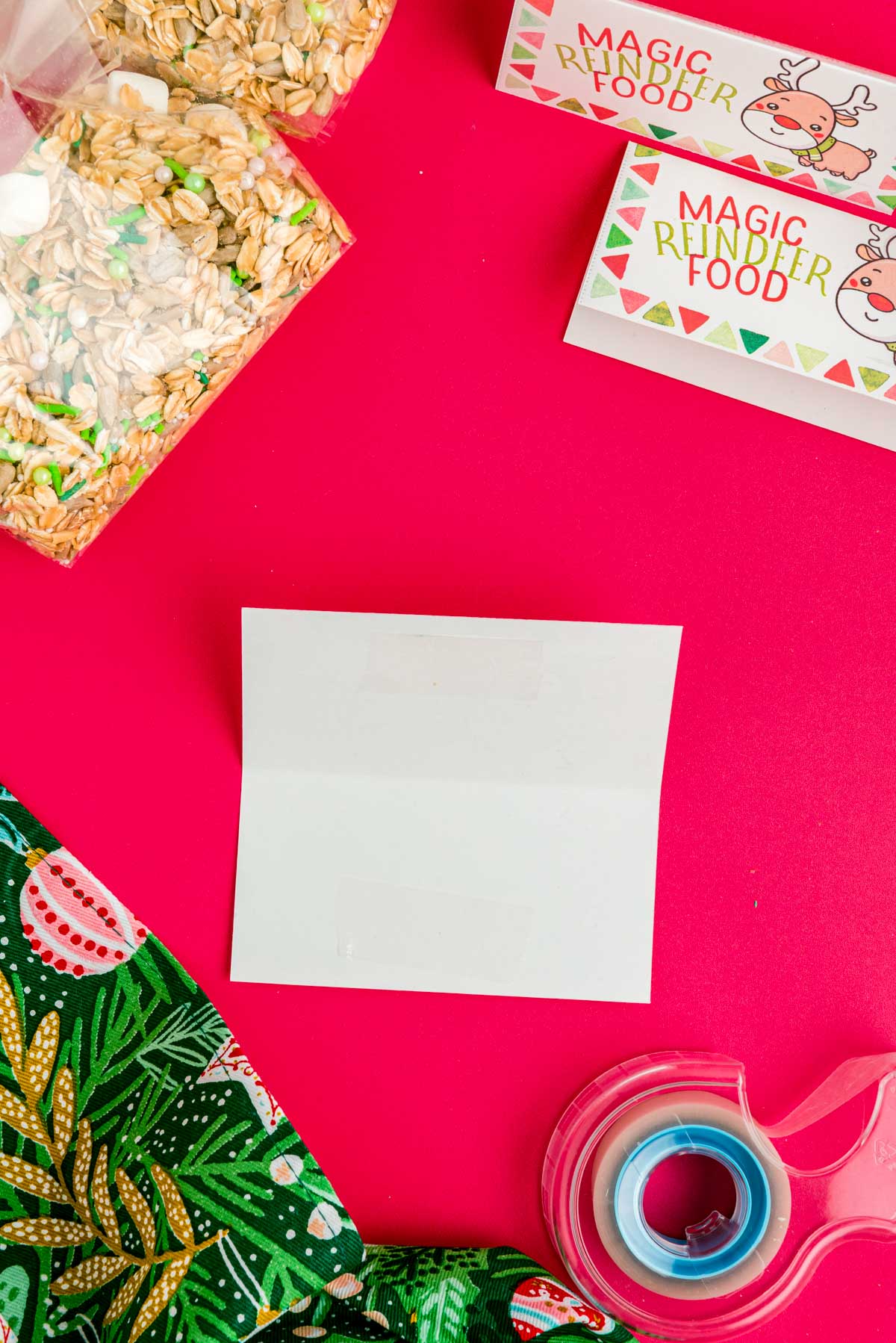 Magic reindeer food labels being prepared with double stick tape on a red surface.