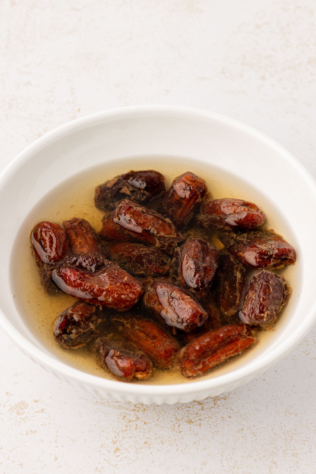 Dates soaking in a bowl of hot water.