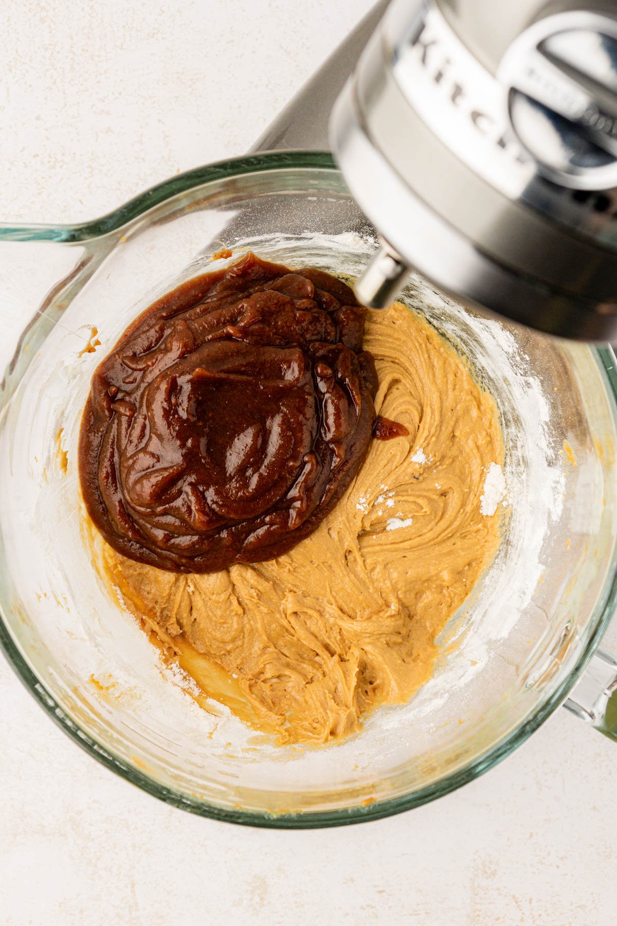 Date puree being added to batter in a glass mixing bowl.