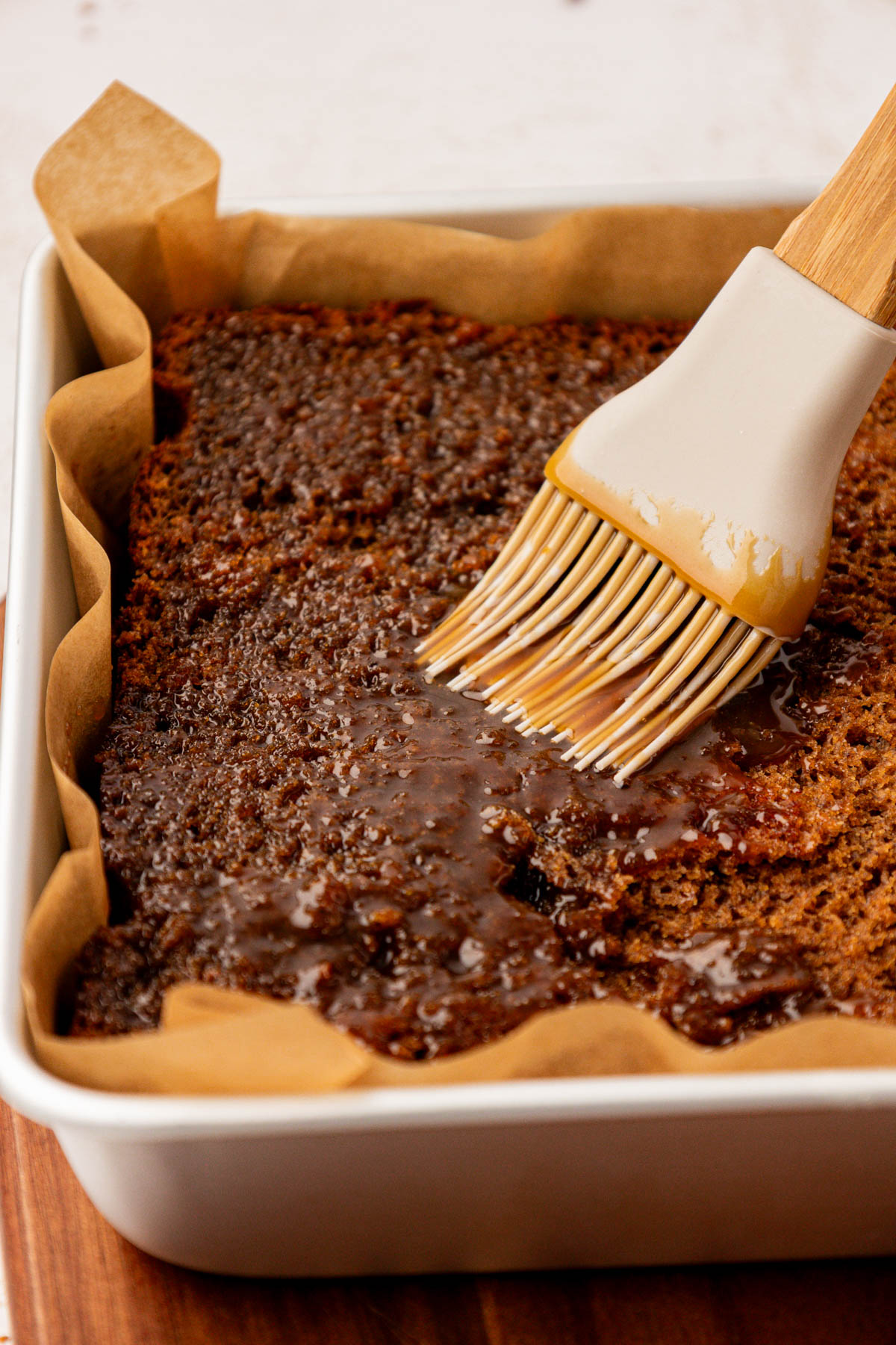 Toffee pudding cake being brushed with toffee sauce.