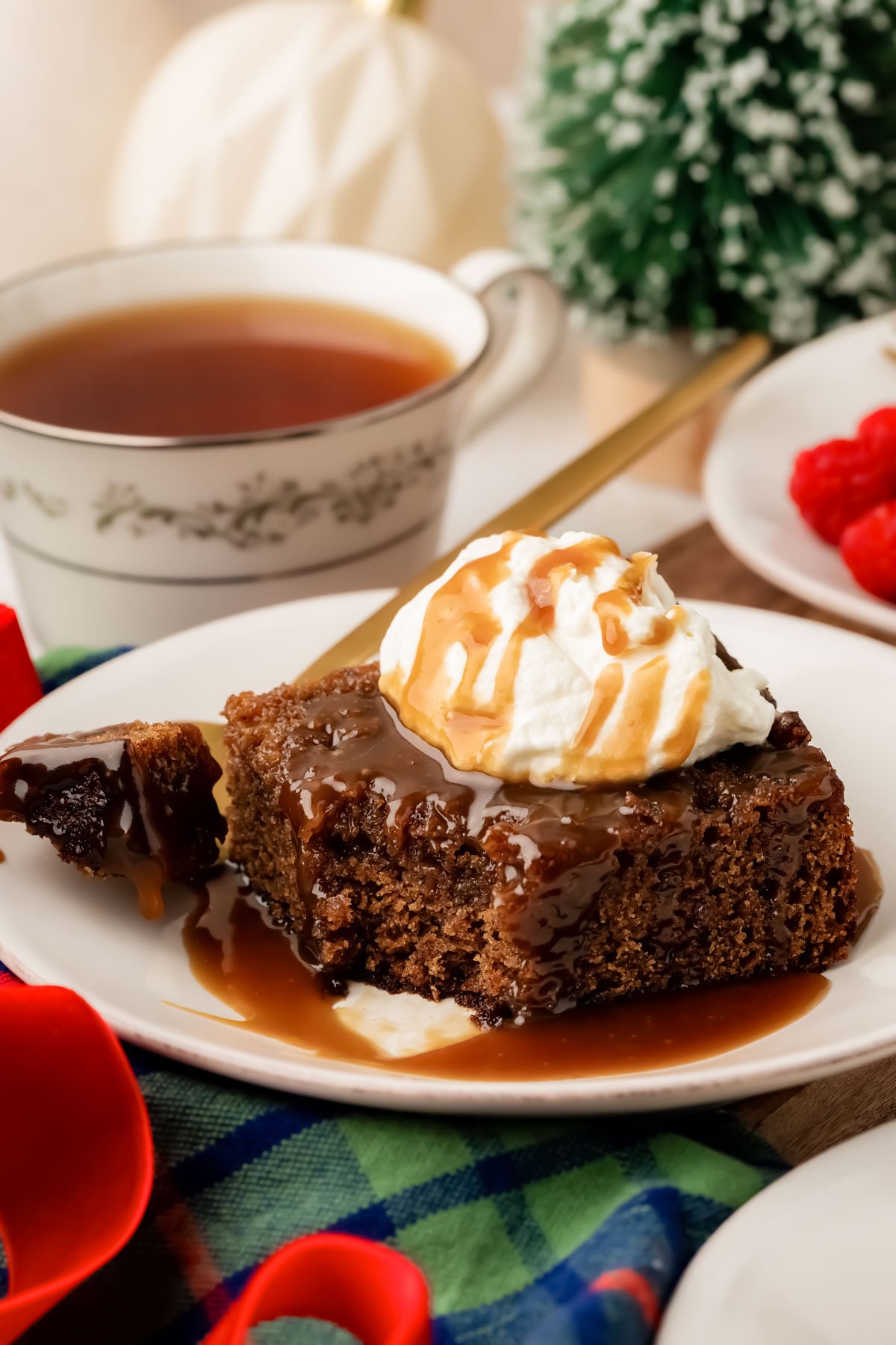 A slice of sticky toffee pudding on a white plate with a bite taken out of it.