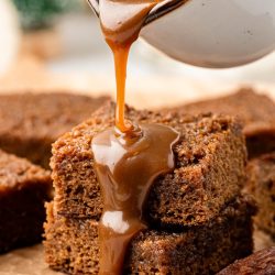 Toffee sauce being poured over sticky toffee pudding.