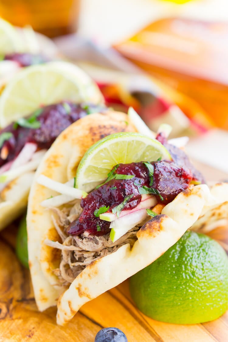 Pulled Pork Tacos with Blueberry Barbecue Sauce are perfect for game days and weeknights! A pork shoulder is slow cooked in root beer, topped with an apple slaw and homemade blueberry barbecue sauce all nestled in delicious naan bread!
