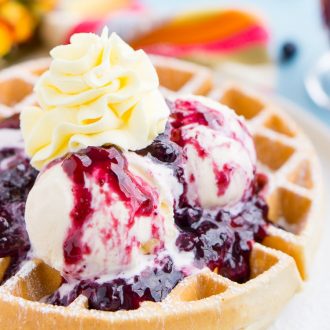 Belgian Waffles with Mango Blueberry Compote are a flavorful and fun brunch dish! Fluffy waffles, vibrant wild blueberries, and luscious mangoes, topped with ice cream and whipped cream!