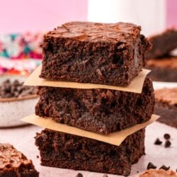 A stack of three thick brownies on a table.