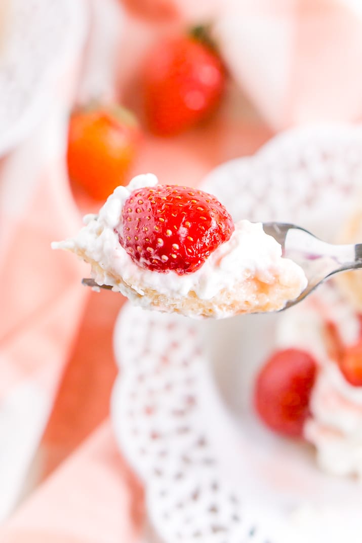 Close up photo of a fork with a bite of strawberry shortcake on it.