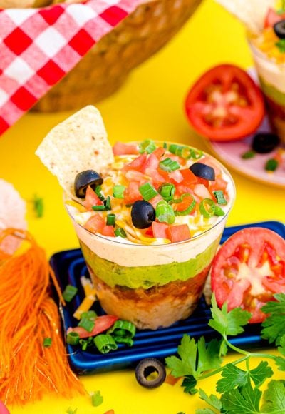 7 Layer Dip Cups on a small blue board on a yellow surface.