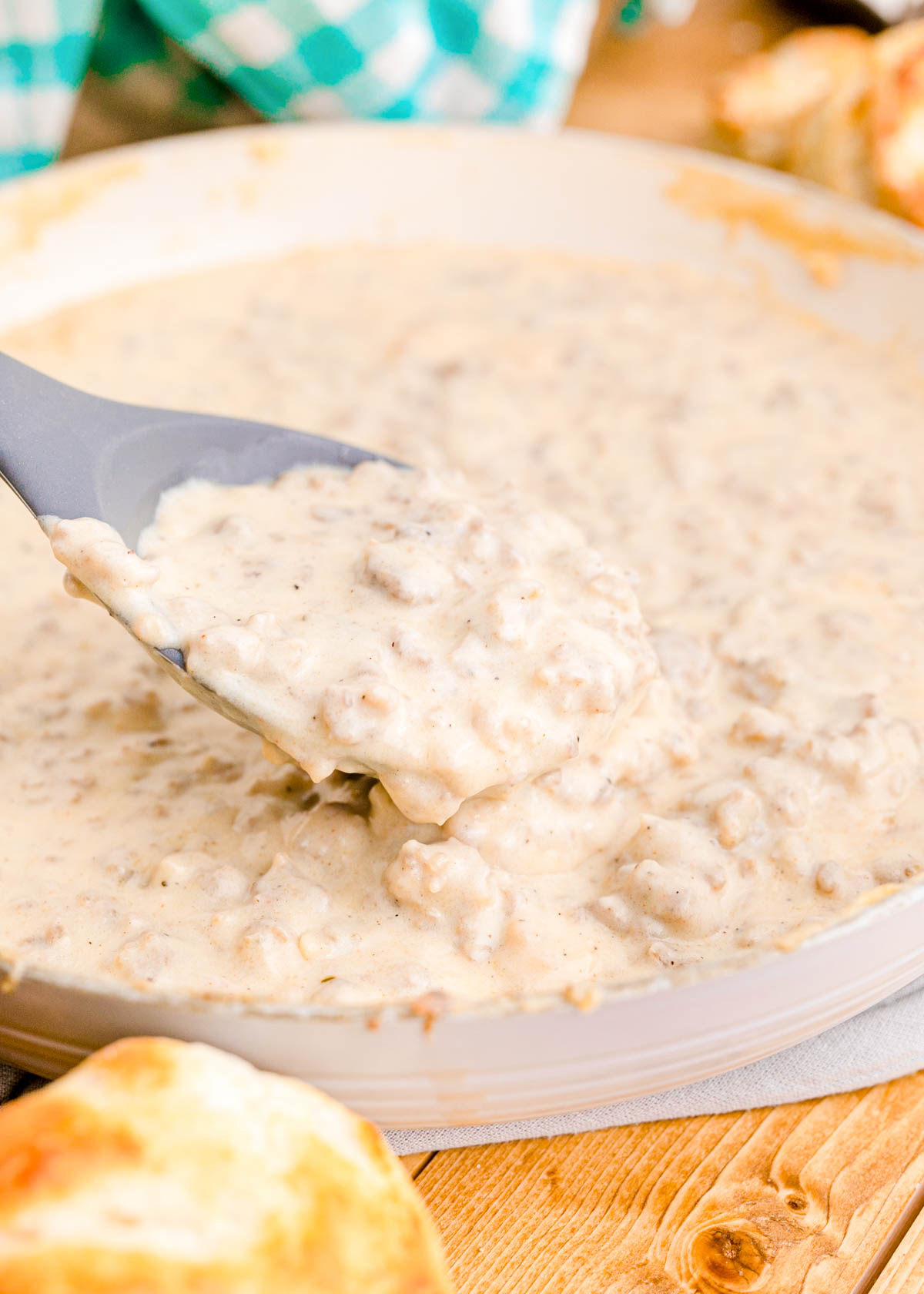 Sausage gravy being spooned out of a skillet.