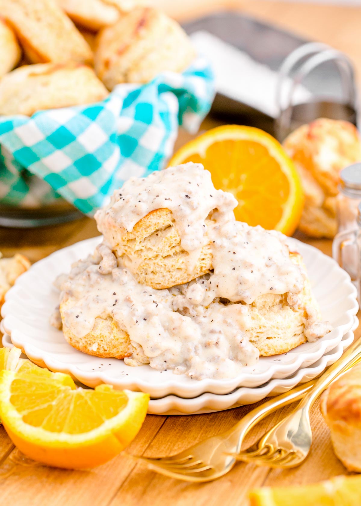 Biscuits and sausage gravy on a white plate on a wooden table.