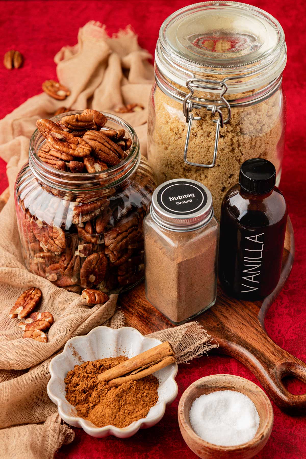 Ingredients to make candied pecans on a red table.