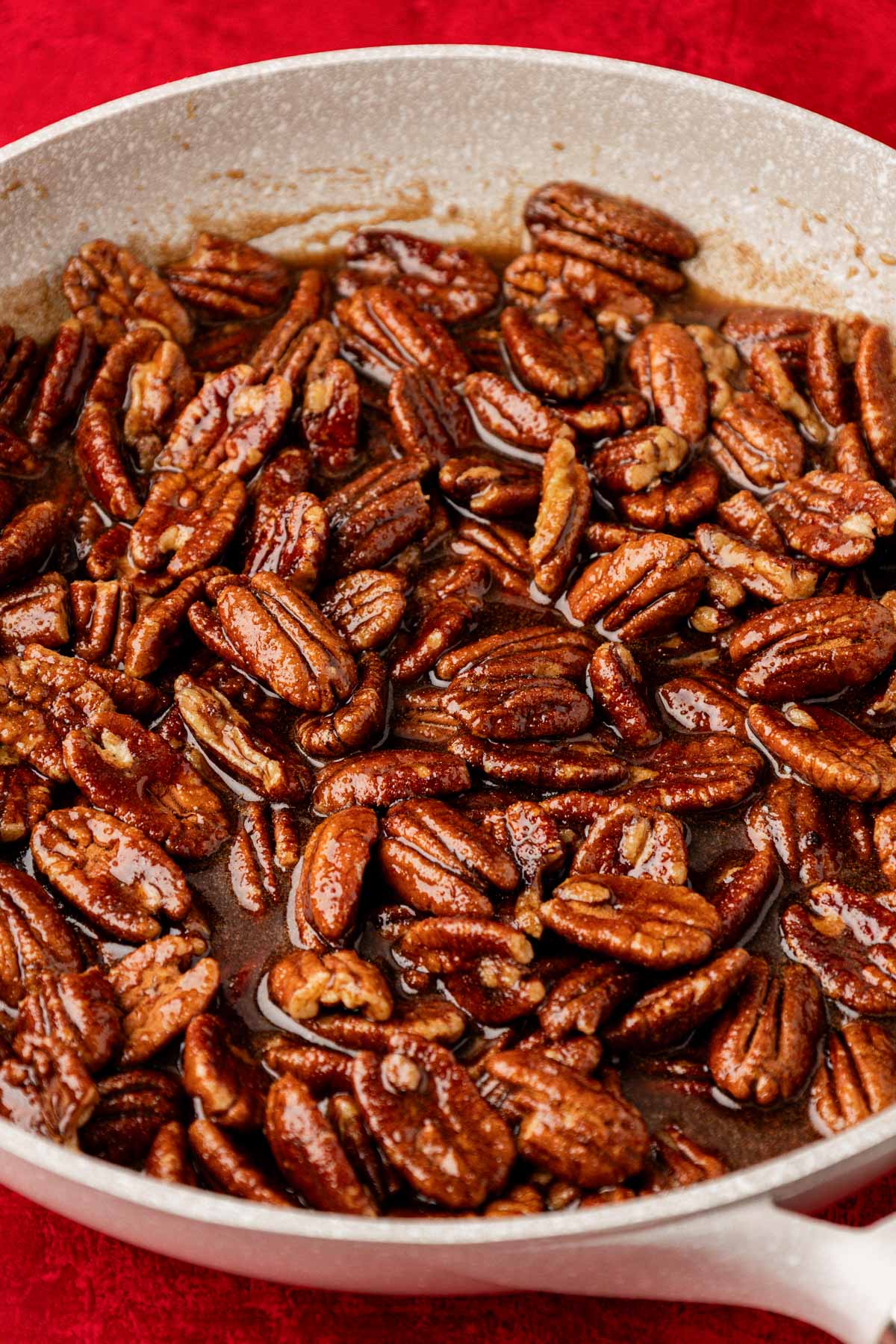Pecans stirred into brown sugar and water on a skillet.