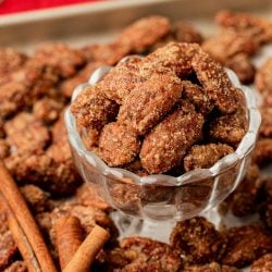 Candied Pecans in a glass dish surrounded by more.