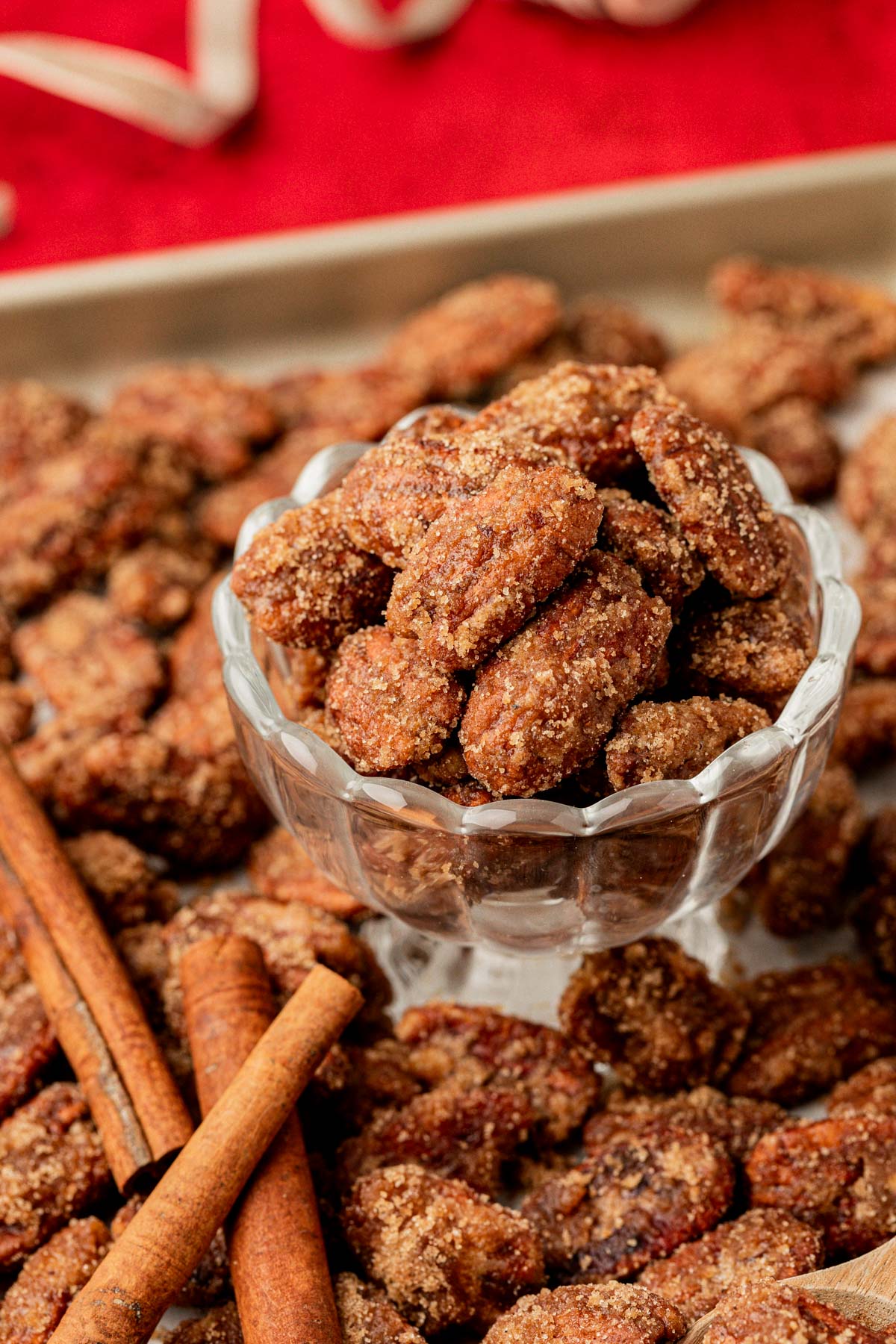 Candied Pecans in a glass dish surrounded by more.