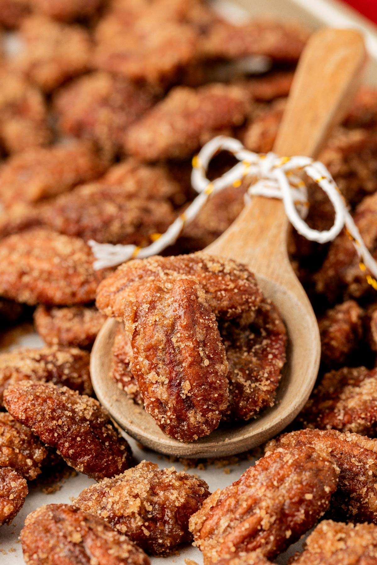 A wooden spoon scooping caramelized pecans.