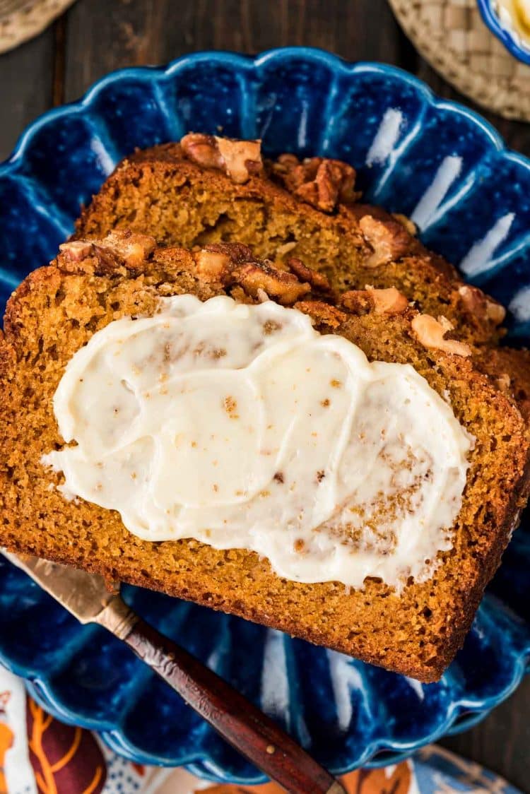 Slices of spiced pumpkin bread with butter on a blue plate.