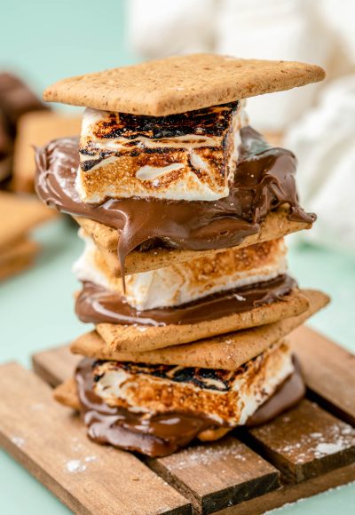 S'mores made with homemade marshmallows stacked on a wooden coaster.