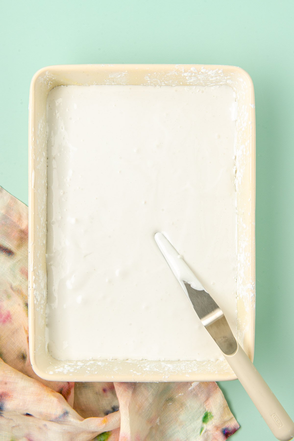 Marshmallow cream in a 9x13-inch baking pan ready to set.