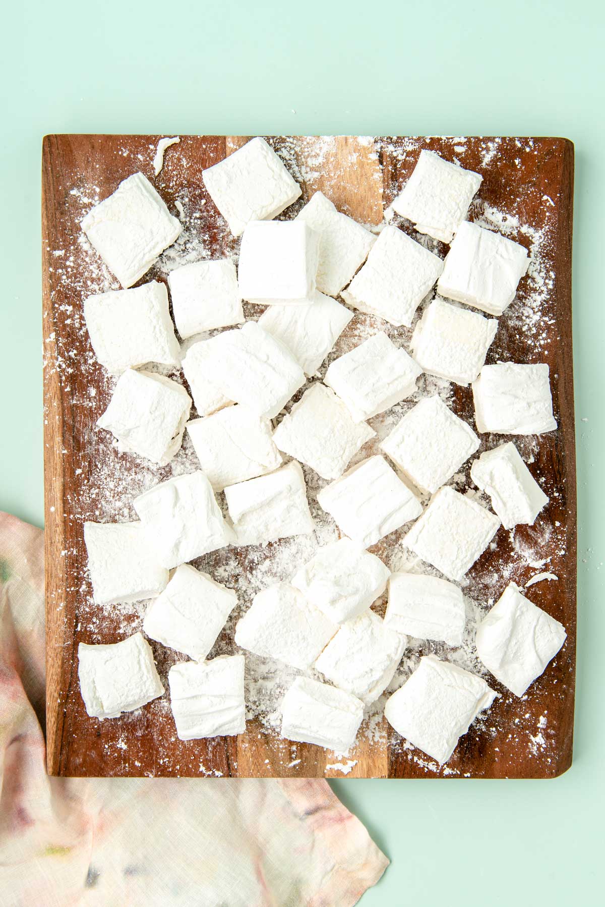 Cubed marshmallows on a wooden cutting board.