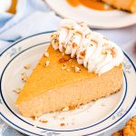 A slice of pumpkin cheesecake on a blue rimmed white plate.