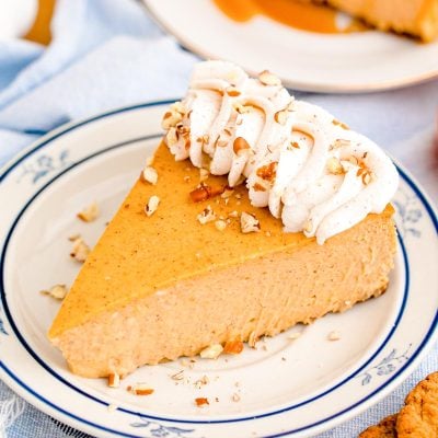 A slice of pumpkin cheesecake on a blue rimmed white plate.
