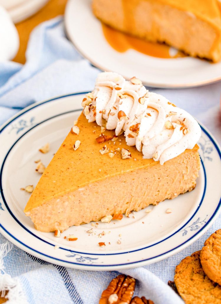 A slice of pumpkin cheesecake on a blue rimmed white plate.