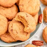 Close up photo of pumpkin snickerdoodles on a light blue plate with pecans scattered around.