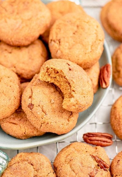 Close up photo of pumpkin snickerdoodles on a light blue plate with pecans scattered around.