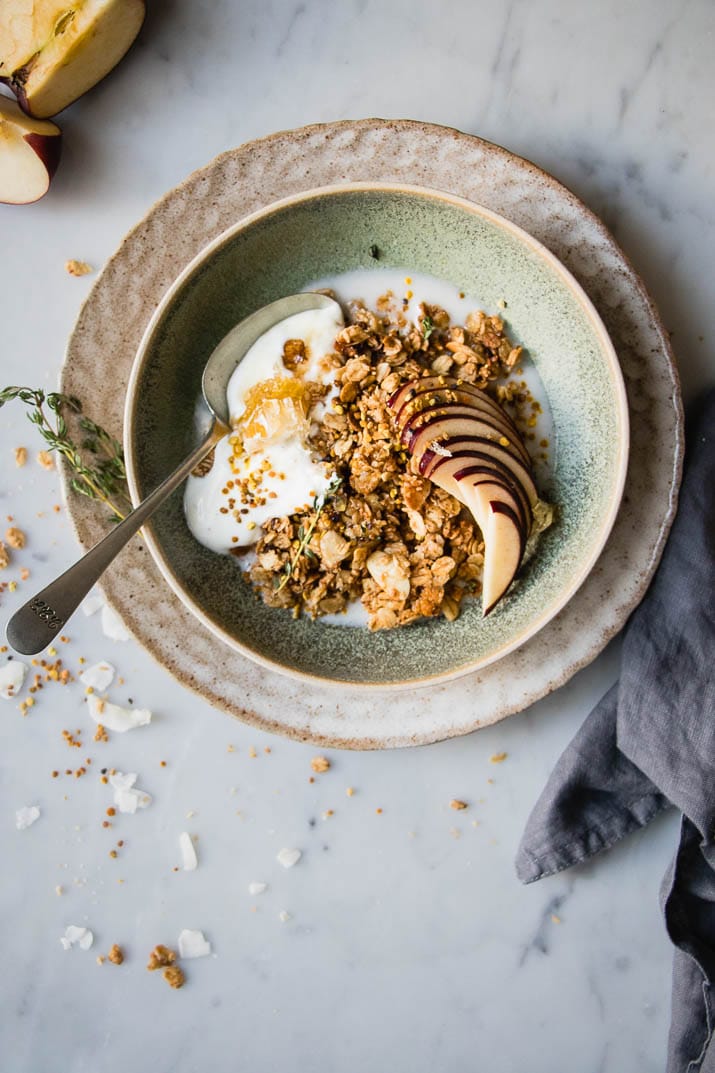 This Breakfast Bowl is loaded with warm granola, apple, yogurt, bee pollen, coconut, almonds, and more for a delicious and hearty breakfast.