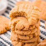 Close up photo of peanut butter cookies stacked on a striped napkin.