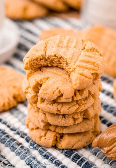 Close up photo of peanut butter cookies stacked on a striped napkin.