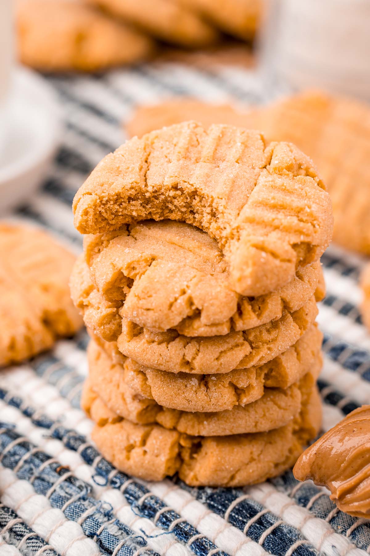 Close up photo of peanut butter cookies stacked on a striped napkin.