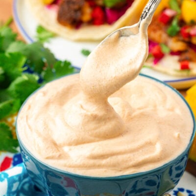 Close up of a spoon scooping into a bowl of fish taco sauce.