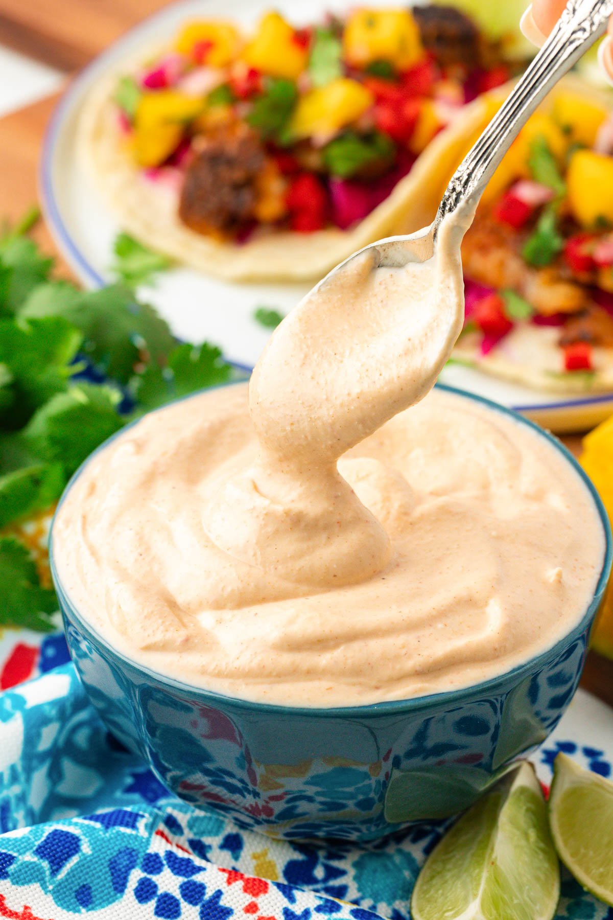 Close up of a spoon scooping into a bowl of fish taco sauce. 