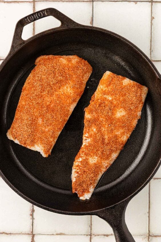 Seasoned cod in a cast iron skillet.