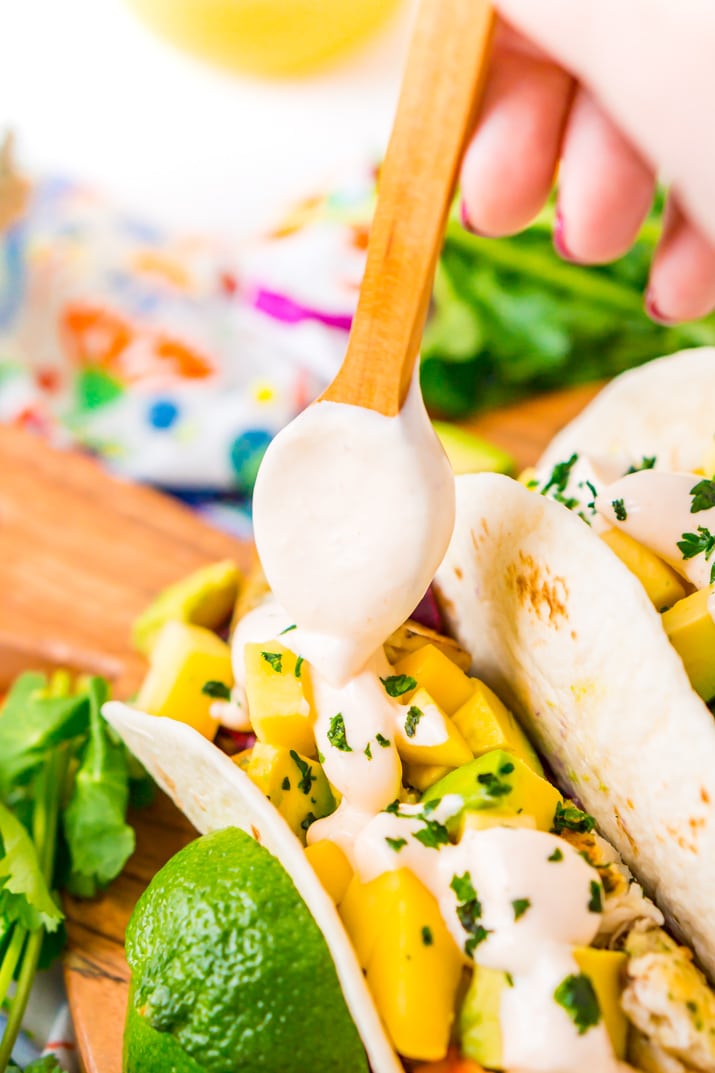 Crema being applied to tacos with a spoon