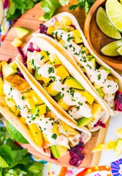 This Fish Tacos Recipe is an easy dinner recipe made with frozen tilapia, flour tortillas, pickled cabbage, avocado, mango, cilantro, and lime juice. It's a simple and light and only takes about 30 minutes to make!