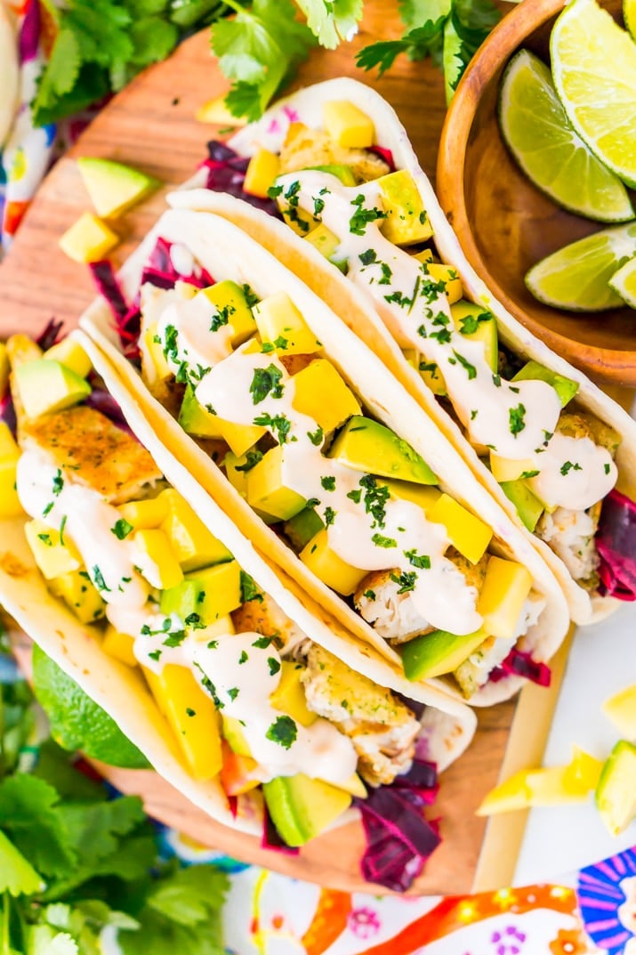 This Fish Tacos Recipe is an easy dinner recipe made with frozen tilapia, flour tortillas, pickled cabbage, avocado, mango, cilantro, and lime juice. It's a simple and light and only takes about 30 minutes to make!