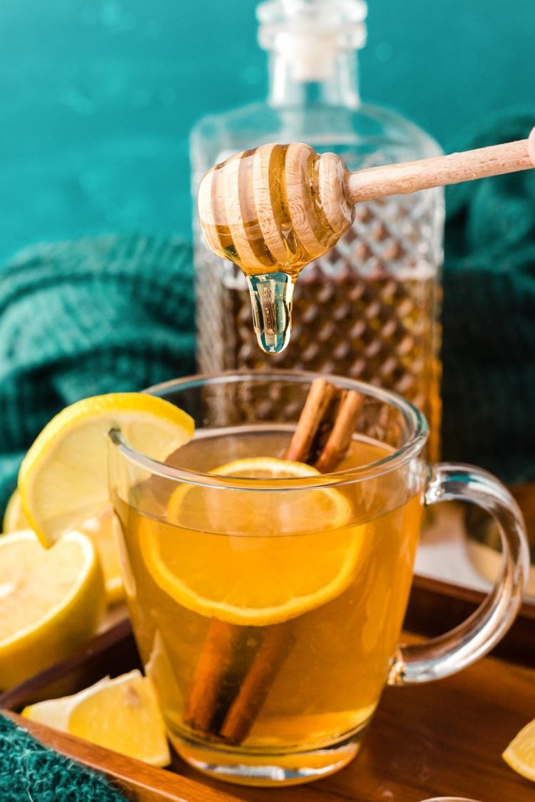 Honey being added to a mug of tea.
