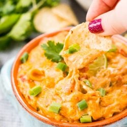 This Slow Cooker Chicken Queso Dip is an easy and addicting party dip made with shredded chicken, cheese, green chiles, tomatoes, green onions, and lots of spice!