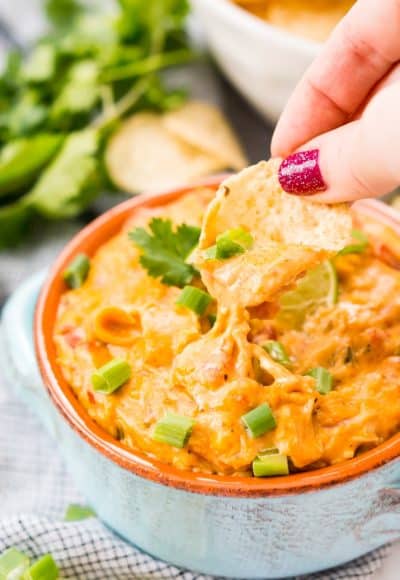 This Slow Cooker Chicken Queso Dip is an easy and addicting party dip made with shredded chicken, cheese, green chiles, tomatoes, green onions, and lots of spice!