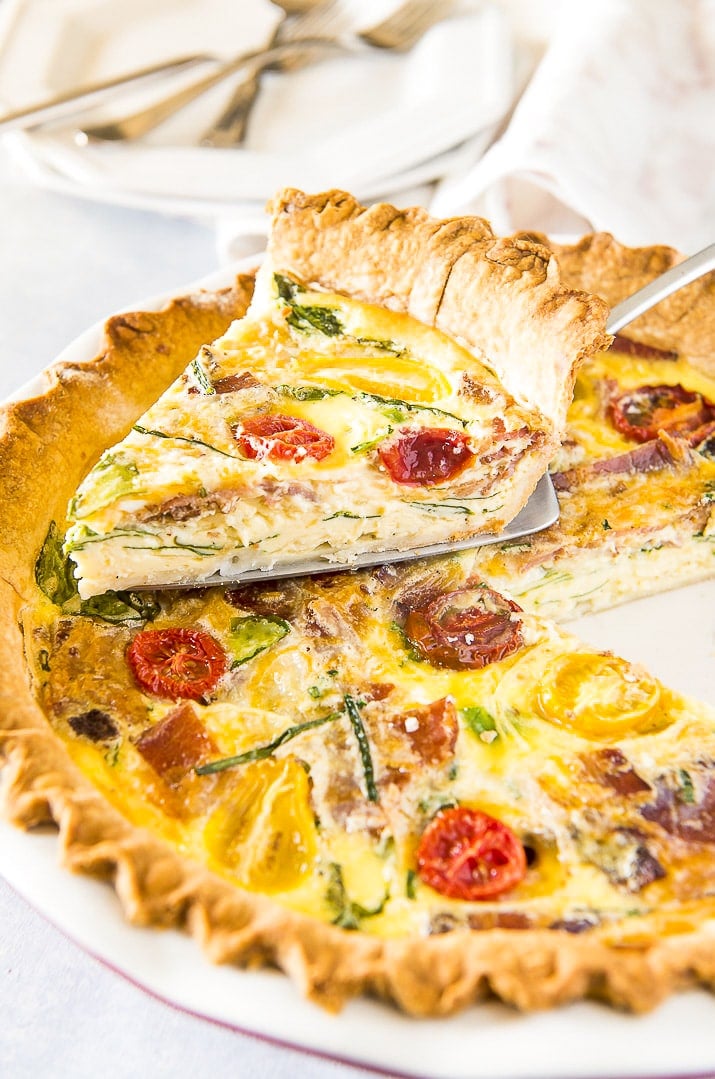 Slice of bacon spinach quiche lorraine on pie server