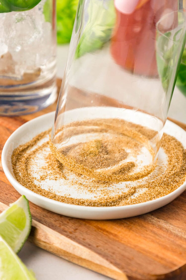 The rim of a glass being dipped in celery salt.