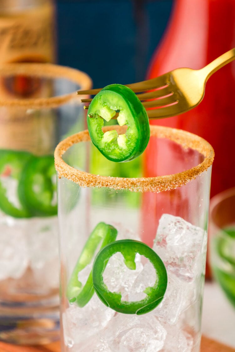Sliced jalapenos being added to glasses with ice.